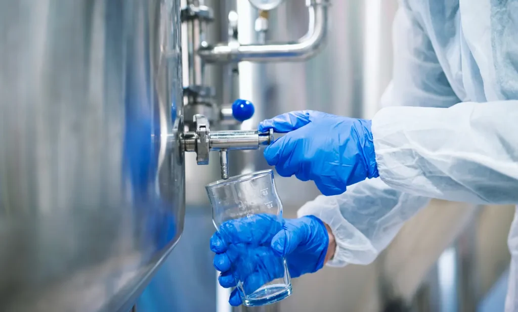 Clean filtered water stream with technician reviewing data on laptop