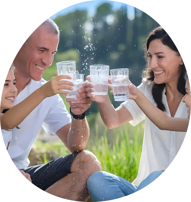 Smiling family outdoors clinking glasses of clean water, illustrating the positive health impact of water filtration
