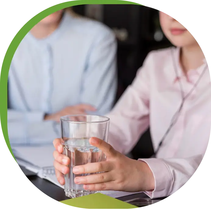 Close-up of hands pouring water into a glass, representing community giving and support